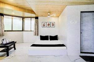 Una habitación de hotel con cama, escritorio con tetera y ventana con cortinas.