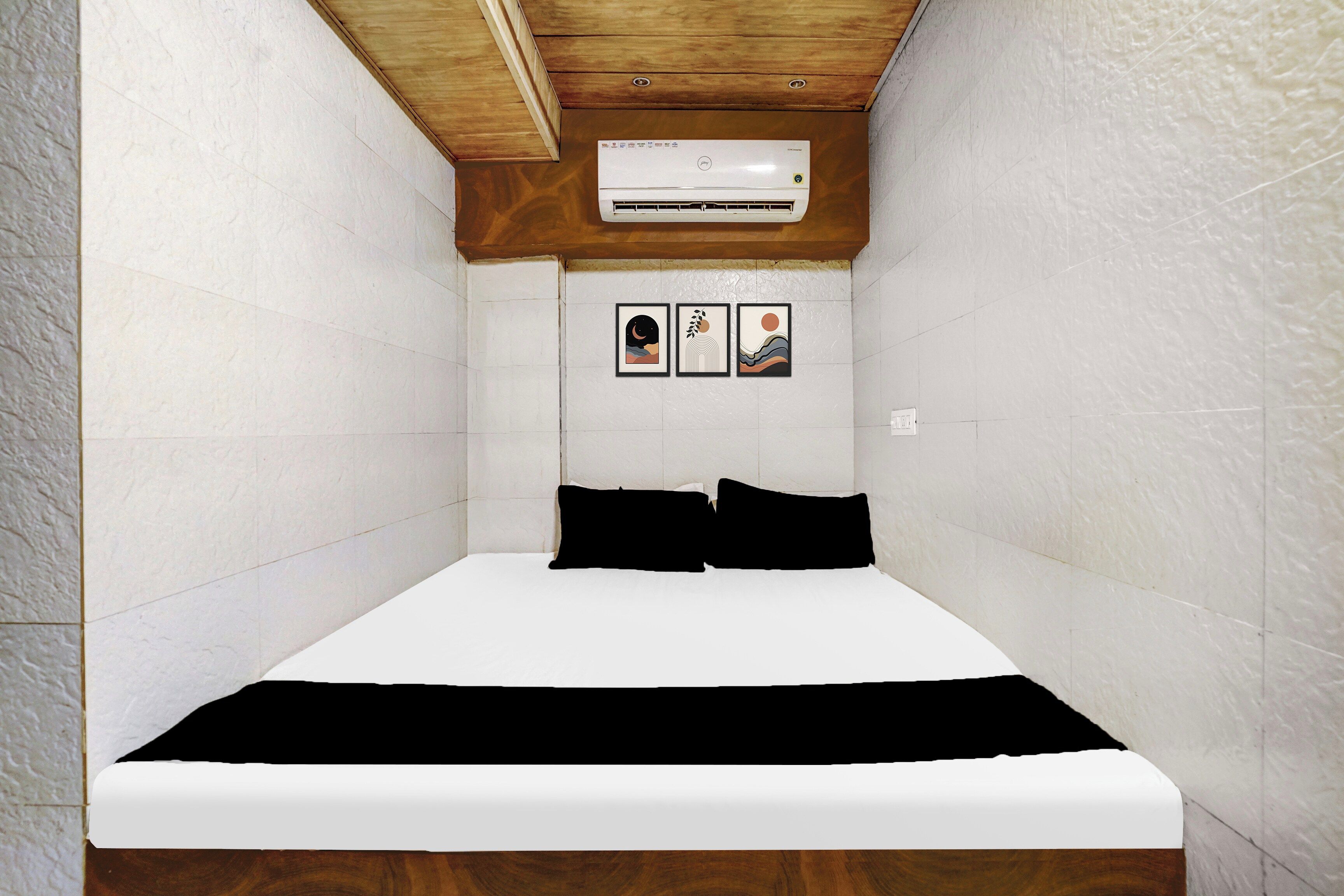 Una habitación pequeña y estrecha con una cama, paredes blancas y un techo de vigas de madera.