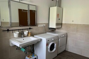 A laundry area with a washing machine, a dryer, a sink, and a mirror. - Lakeside with mountain views, ground floor (Arrach)