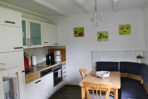 A compact kitchen with a dining area, including a table and chairs, and a built-in bench. - Lakeside with mountain views, ground floor (Arrach)