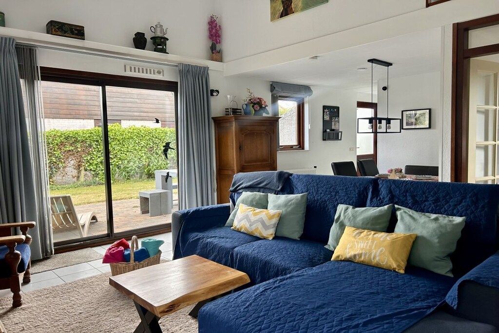 A living room with a blue sofa, a wooden coffee table, and a view through a glass door to an outdoor area.