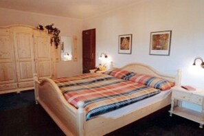A bedroom with a bed, bedside table, wardrobe, and wall-mounted light fixtures. - Panoramic holiday apartment with lake view (Schalkenmehren)