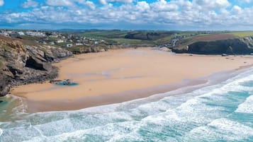 Una playa costera con arena, olas y un pueblo lejano.