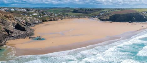 A coastal beach with a sandy shore, waves, and a distant town.