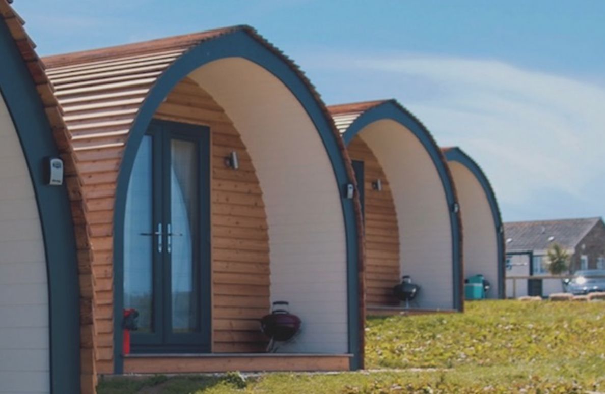Una hilera de cabañas de madera con puertas y ventanas de arco, cada una con un pequeño porche.