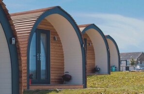 Una hilera de cabañas de madera con puertas y ventanas de arco, cada una con un pequeño porche.