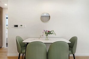 A dining area with a round mirror, a vase with flowers, and three chairs. - Elegant Urban Retreat in the Heart of Epping (Epping)