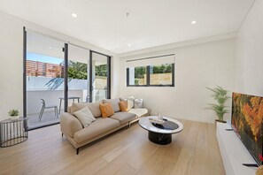 A modern living room with a sofa, coffee table, and a painting on the wall. - Elegant Urban Retreat in the Heart of Epping (Epping)