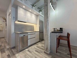 Une cuisine moderne dotée d’appareils électroménagers intégrés, un coin repas avec une chaise en bois et un escalier.