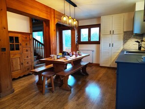 A wooden dining table with benches, a kitchen area with cabinets, and a staircase leading to another level. - Le Montagnard (8 people) View of Mont Blanc & covered parking (Saint-Gervais-les-Bains)