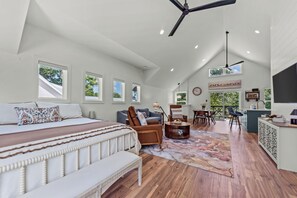 A spacious loft bedroom with a large bed, a seating area with a sofa and chairs, a dining table, and a kitchen area with a view. - Charming apartment in marvelous Jefferson with cool AC breeze (Jefferson)