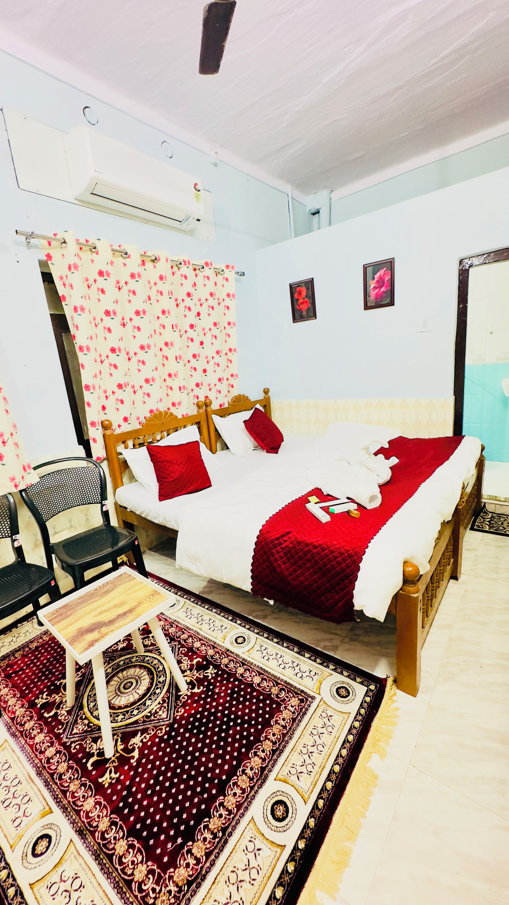 Una habitación con una cama, una silla, una mesita pequeña y una alfombra estampada.