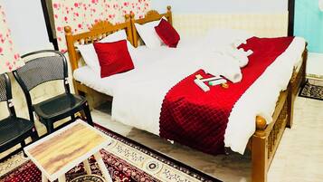 Una habitación con una cama, una silla, una mesita pequeña y una alfombra estampada.
