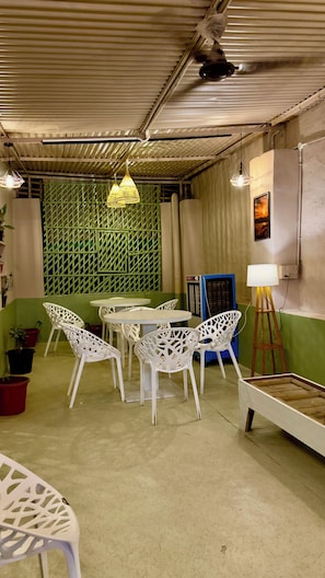 A room with a green lattice partition, white chairs, a round table, and a standing lamp. - Hotel Hermosa Pushkar (Pushkar)