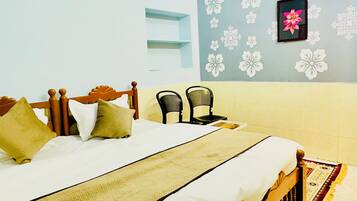 Un dormitorio con una cama, dos sillas, un ventilador de techo y una pared con estampado floral.