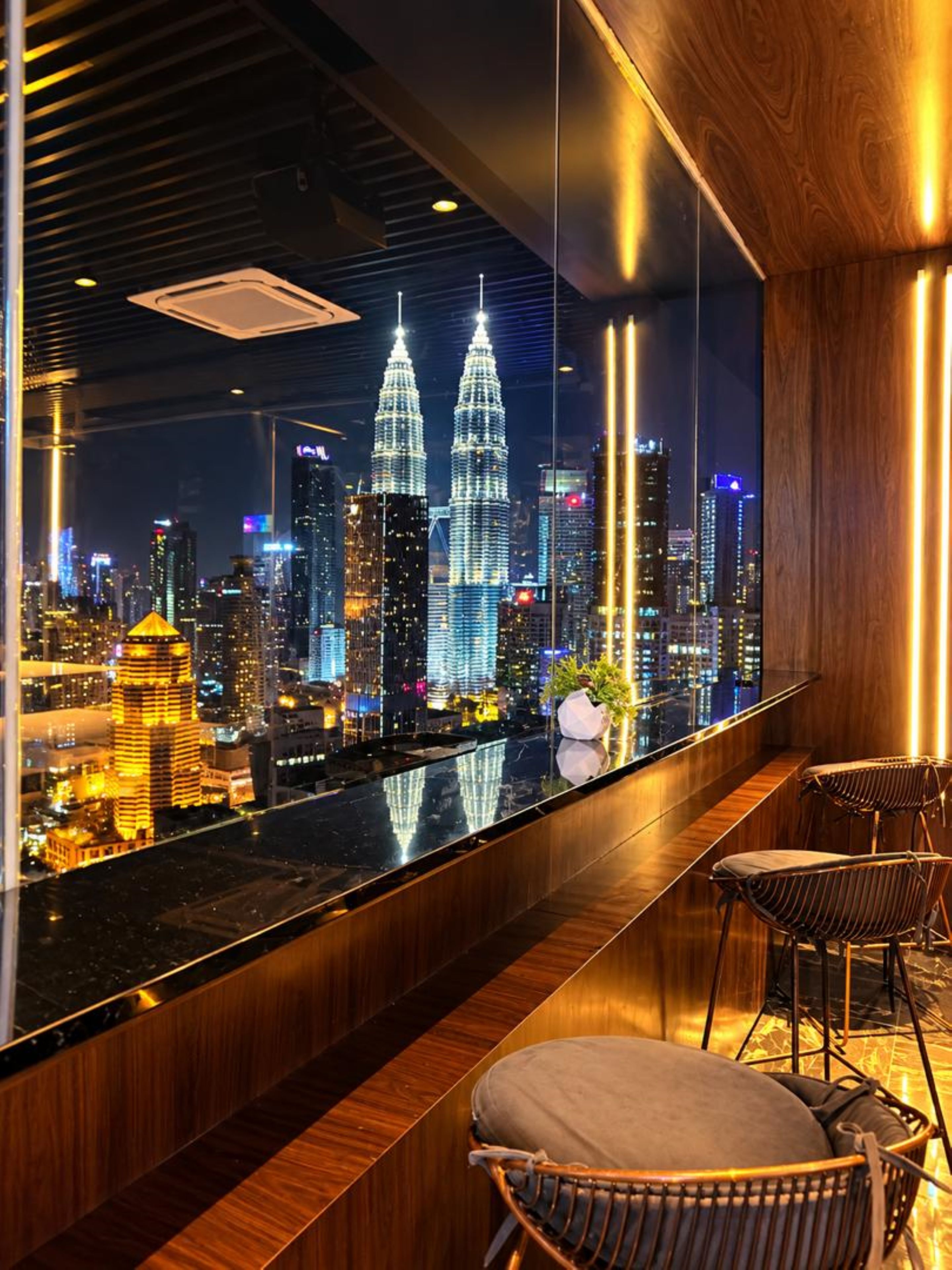 Un interior moderno con vistas a un horizonte urbano, incluyendo un edificio destacado con dos torres gemelas.