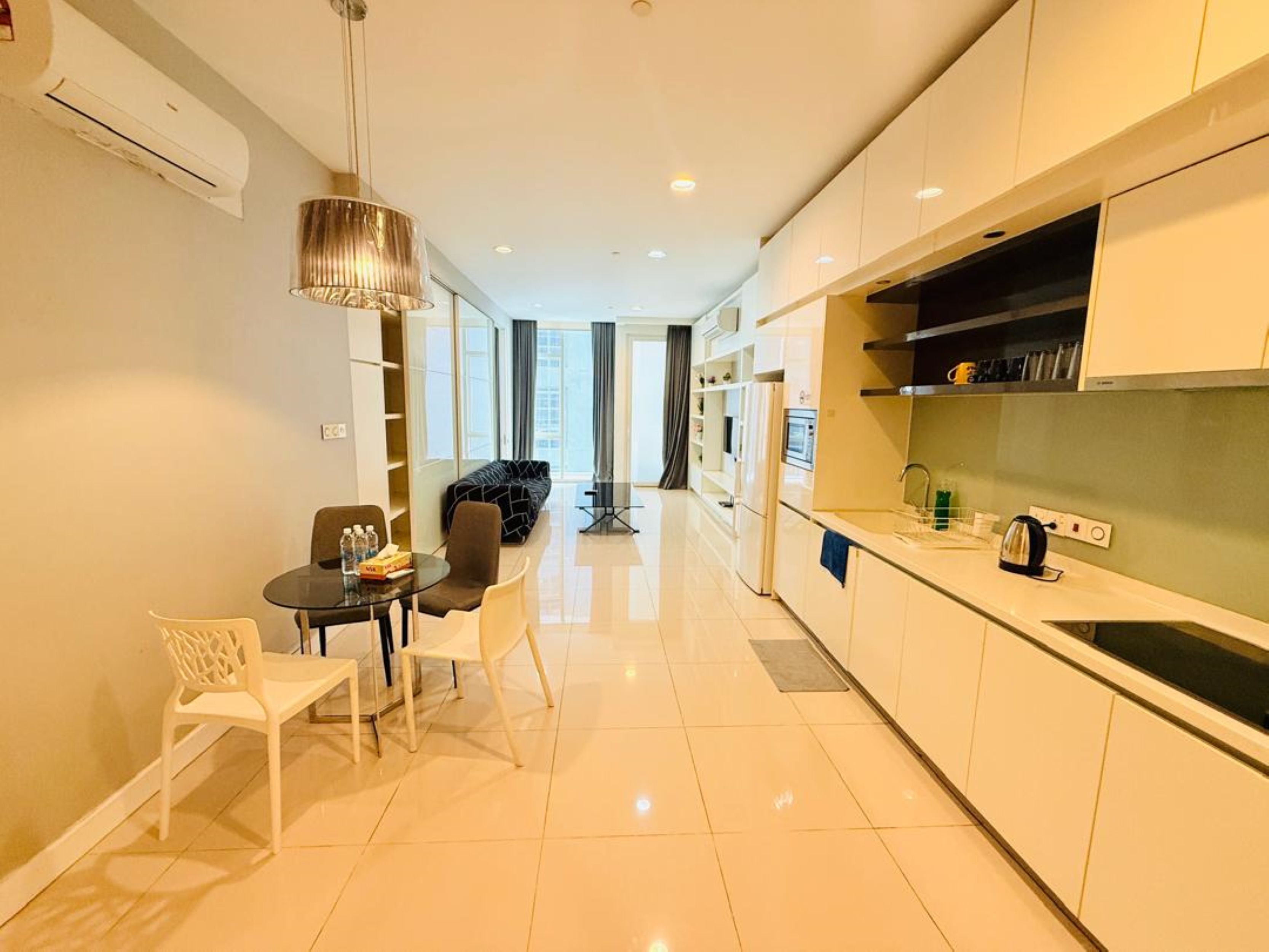 A modern kitchen with white cabinets, a dining area with a table and chairs, and a view to the living room.