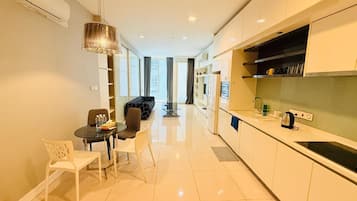 A modern kitchen with white cabinets, a dining area with a table and chairs, and a view to the living room.