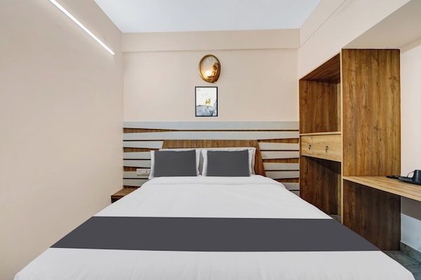 A modern bedroom with a bed, bedside tables, a wooden headboard, and a wall-mounted light fixture.