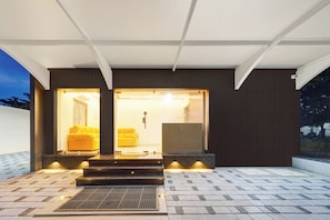A modern building with a dark facade, large glass doors, and a yellow sofa visible inside.