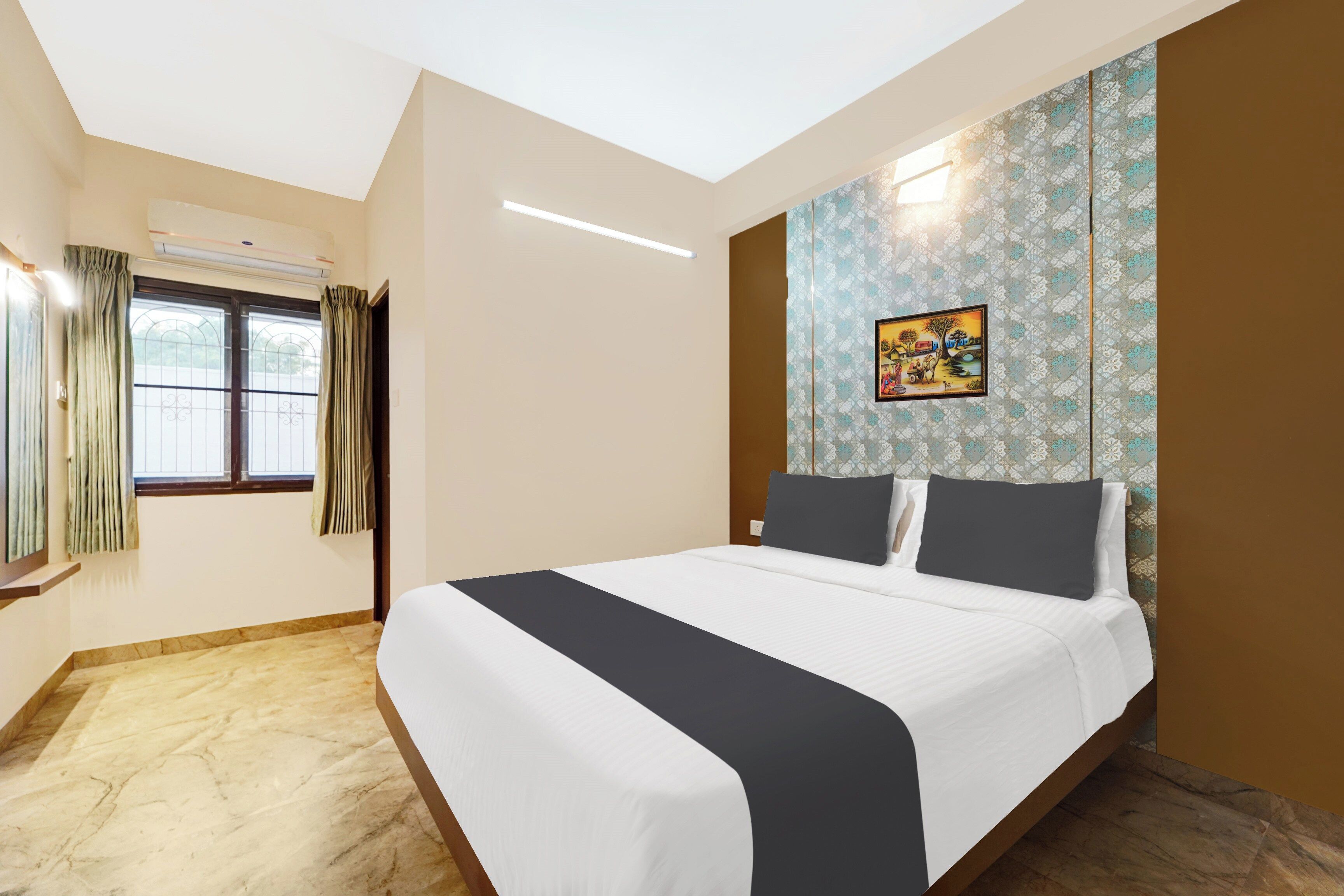 Una habitación de hotel con cama, ventana con cortinas, pared con papel tapiz estampado y un cuadro.