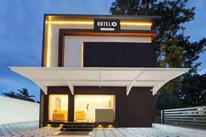 Un hotel moderno con un letrero llamativo, un acceso cubierto y un interior visible que incluye un sofá.