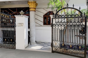 A gated entrance with a white pillar and ornate metalwork.
