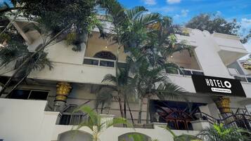 Un hotel con letrero, varios balcones y palmeras.