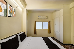 Quarto de hotel com uma cama, janela, ar condicionado e guarda-roupa.