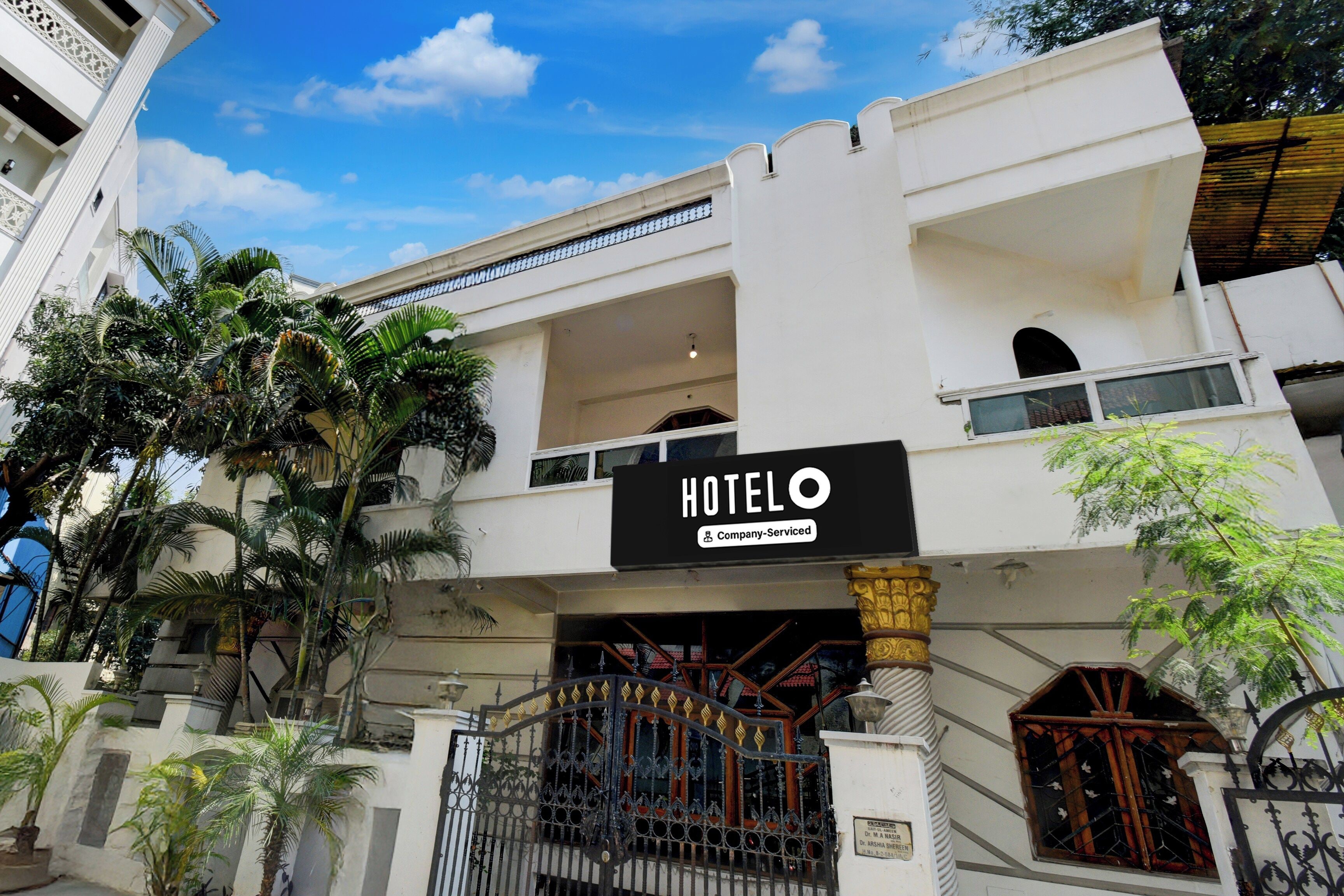 A hotel entrance with a sign, a gated entrance, and a staircase leading to the upper floor.
