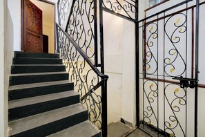 A staircase with black steps and a black handrail, leading to a room with a white door and a decorative metal gate.