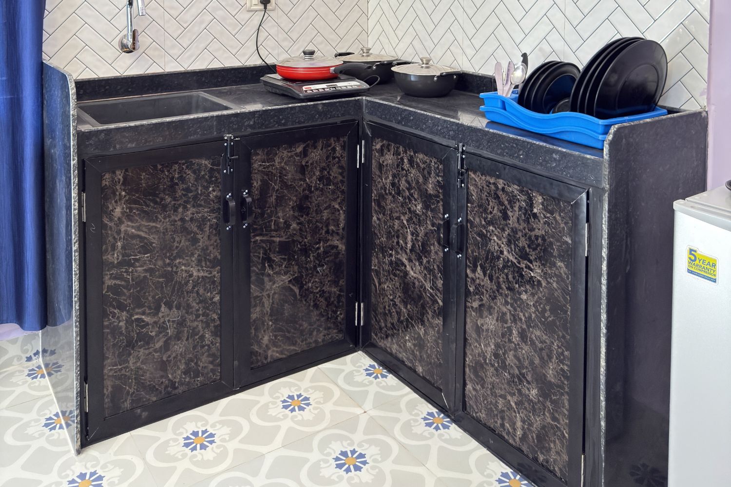 A kitchen with a corner cabinet, a scale, a frying pan, and a dish rack.