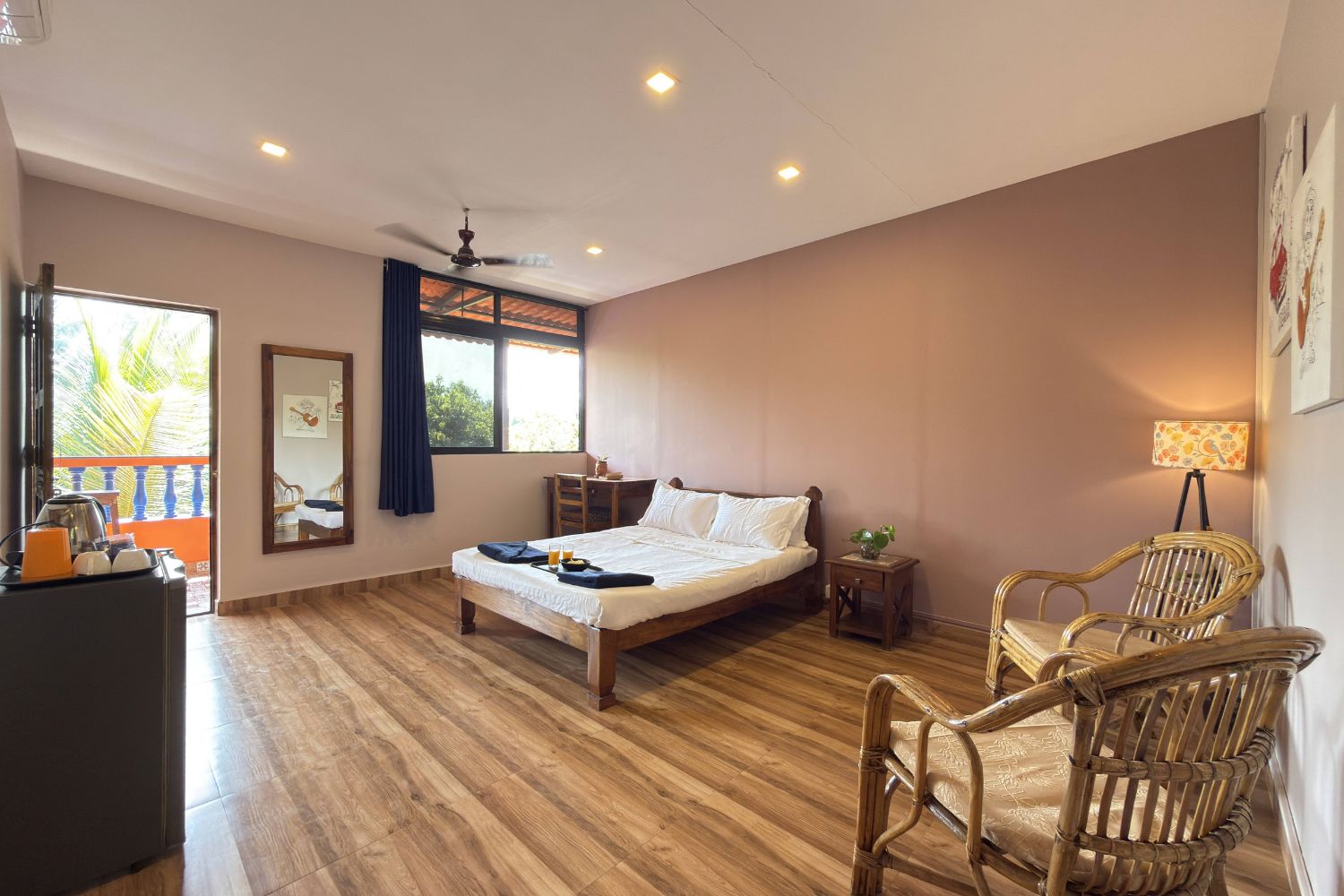 Un dormitorio con cama, mesitas de noche, escritorio, silla, balcón y ventilador de techo.