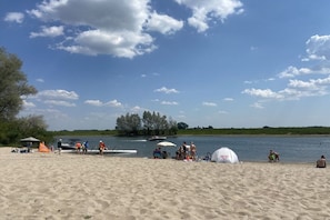 Hiekkainen ranta, jossa on teltoja, ja järvi.