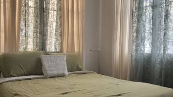 A bedroom with a bed, curtains, and a door.