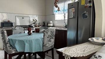 A kitchen with a dining table, chairs, a refrigerator, and a microwave.