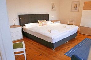 A bedroom with a bed, bedside tables, a chair, and a rug. - Holiday apartment with 1 bedroom (Kappeln)