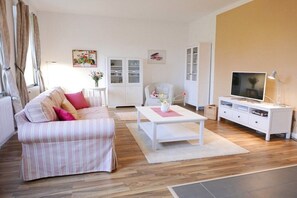 Ein Wohnzimmer mit einer Couch, einem Couchtisch, einer TV-Konsole und einem Schrank.