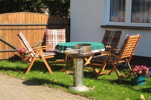 Un patio con una mesa redonda, dos sillas de madera y una lámpara de mesa pequeña.