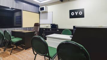 A conference room with a whiteboard, a blackboard, and a sign that reads 'OYO'. There are green chairs and a desk with a computer.