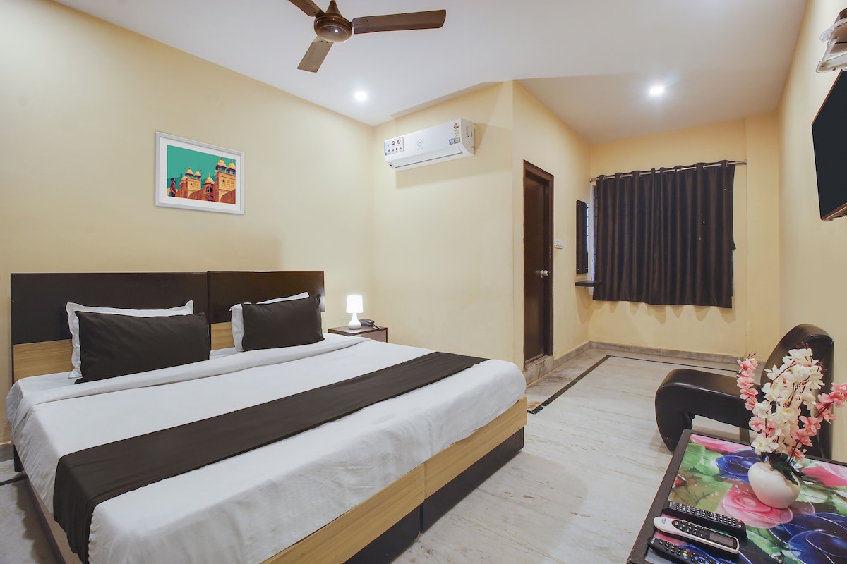 Une chambre d’hôtel avec un lit, une table de chevet, une lampe, un climatiseur et un tableau au mur.