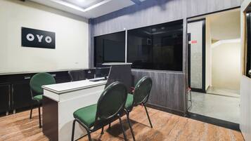 A conference room with a desk, chairs, a 'OYO' sign, a 'No Smoking' sign, and a door leading to another room.