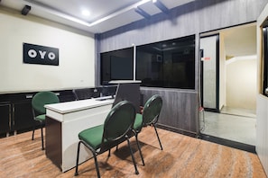 A conference room with a desk, chairs, a 'OYO' sign, a 'No Smoking' sign, and a door leading to another room. - Hotel O Anuguna Tulasi Grand (Hyderabad)
