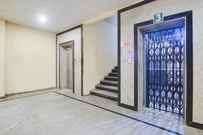 Um corredor com escada que leva a um elevador, identificado com o número 3.