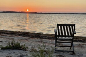 Een bankje met uitzicht op een rustig wateroppervlak tijdens de zonsondergang.