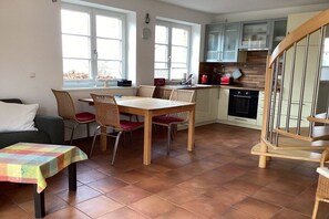 A kitchen with a dining area, a staircase, and a view of the outdoors. - Apartment on the west side (Gager)
