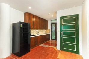 A kitchen with a black refrigerator, wooden cabinets, and a green door. - HÙA 03BR 301 (Đà Nẵng)