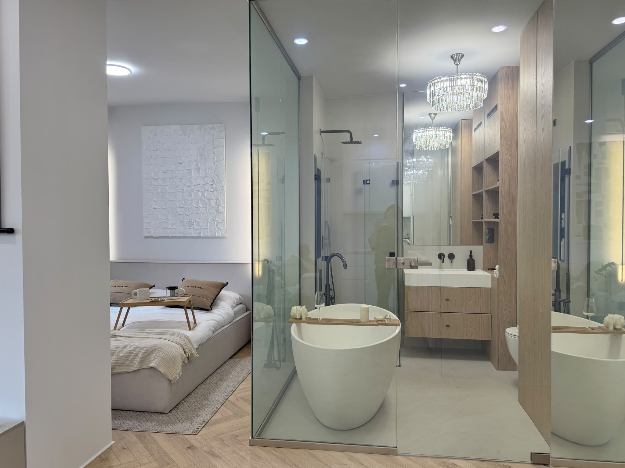 A modern bedroom with a large bed, bedside table, and a glass shower enclosure.
