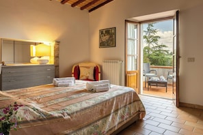 Een slaapkamer met een bed, een dressoir, een raam en uitzicht op de omgeving.