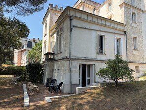A two-story building with a balcony, a door, and a small garden area with outdoor furniture. - New Listing (Royan)